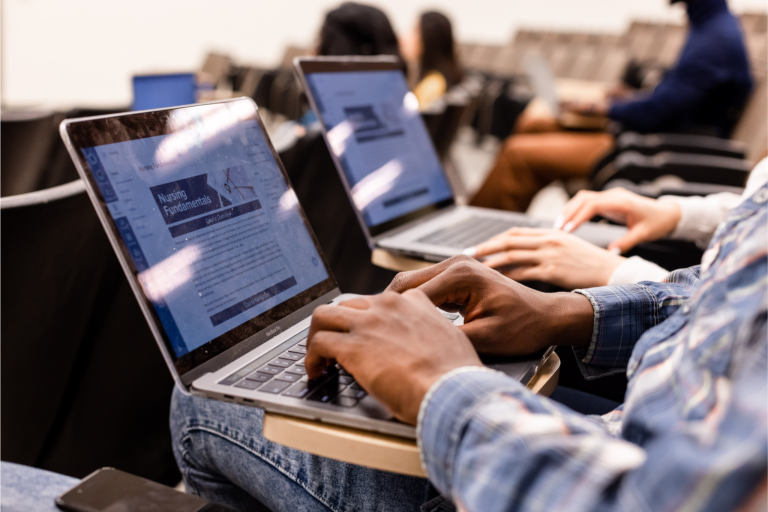 Students using a learning management system on their laptops. They are sitting in a lecture.